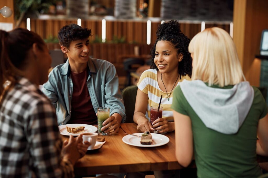 Happy African American woman and her friends enjoying in conversation in a cafe.