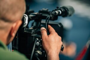 Close-up of a videographer operating a professional camera, focusing on film production equipment.