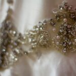 Close-up of intricate beaded embroidery on an elegant satin fabric.