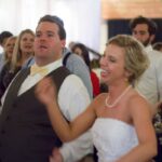 People dancing joyfully at a wedding reception, celebrating with energy and happiness.