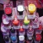 Display of colorful Epic wristwatches in transparent packaging at a retail event.