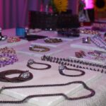 Display of elegant jewelry including bracelets and necklaces on a showcase table with a pink background.