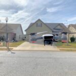 Drone hovering in front of suburban houses under a cloudy sky.