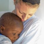 A woman embraces a child lovingly, highlighting compassion and connection in a warm, peaceful setting.