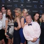 Group of people smiling at a fashion event with branded backdrop.