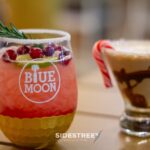 Festive cocktails with cranberries and candy cane garnishes at Blue Moon restaurant, perfect for holiday celebrations.