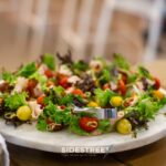 Colorful salad skewers with cherry tomatoes and greens on a marble plate, perfect for a fresh appetizer setting.