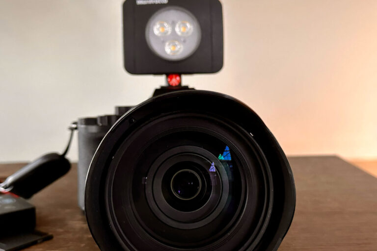 Close-up of a camera lens with attached LED light on a wooden surface, perfect for photography enthusiasts.