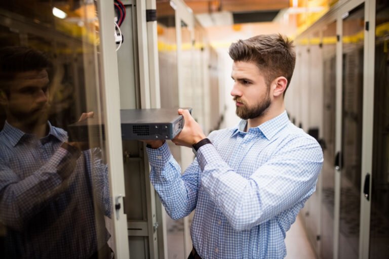 Technician installing server hardware in data center server room.